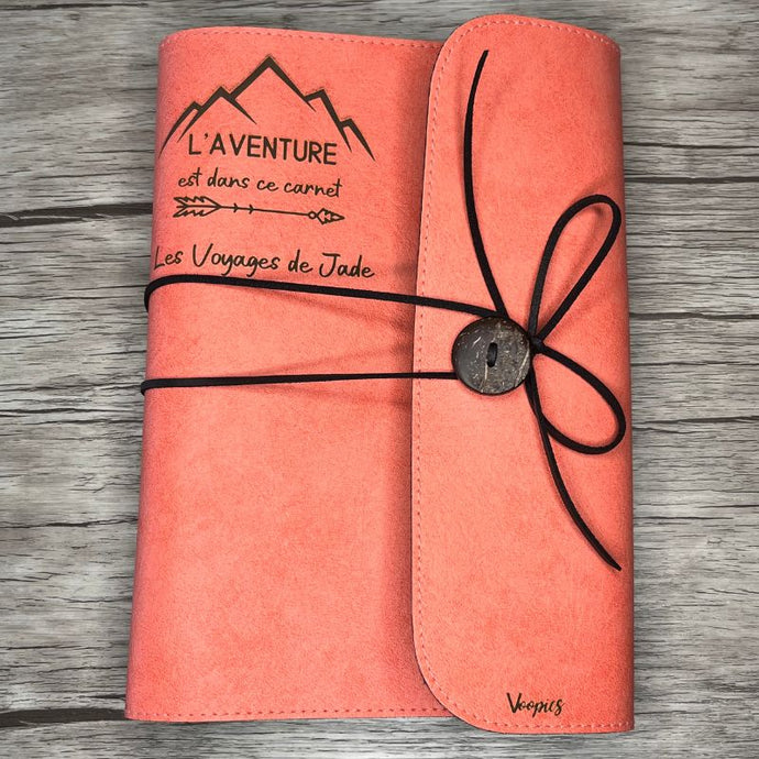 Carnet de voyage saumon personnalisé posé sur un bureau
